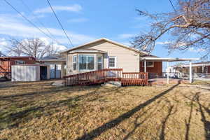 Back of house featuring a yard, a deck, and a storage shed