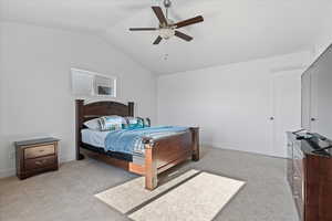 Bedroom with vaulted ceiling, light colored carpet, and ceiling fan