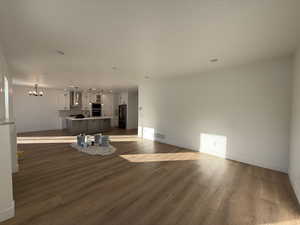 Unfurnished living room featuring hardwood / wood-style flooring, a chandelier, and sink