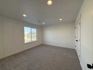 Spare room with a textured ceiling and dark colored carpet