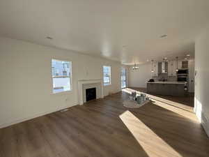 Unfurnished living room featuring an inviting chandelier, sink, a fireplace, and hardwood / wood-style floors