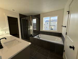 Bathroom featuring vanity, independent shower and bath, and a textured ceiling