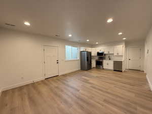 Kitchen featuring appliances with stainless steel finishes, sink, light hardwood / wood-style floors, and white cabinets