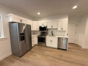 Kitchen featuring white cabinetry, appliances with stainless steel finishes, sink, and light hardwood / wood-style floors