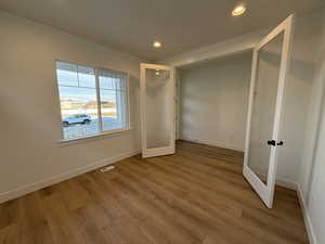 Unfurnished bedroom with french doors and light hardwood / wood-style flooring