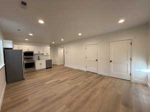 Kitchen featuring stainless steel appliances, light hardwood / wood-style flooring, and white cabinets