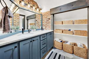 Bathroom with vanity and brick wall