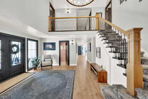 Foyer entrance with a towering ceiling, light hardwood / wood-style floors, and a chandelier