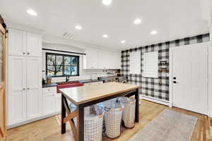 Kitchen featuring a barn door, sink, white cabinets, and light wood-type flooring