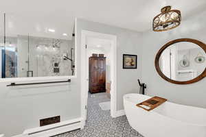 Bathroom with a notable chandelier, plus walk in shower, and a baseboard heating unit