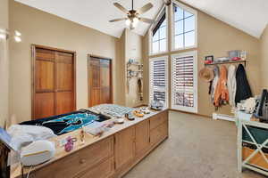 Bedroom featuring high vaulted ceiling, light colored carpet, ceiling fan, and a baseboard heating unit