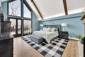 Bedroom with french doors, high vaulted ceiling, baseboard heating, beam ceiling, and light hardwood / wood-style floors