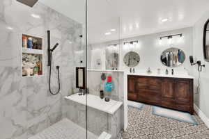 Bathroom featuring a tile shower, vanity, and a textured ceiling