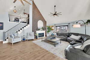 Living room featuring ceiling fan, high vaulted ceiling, and light wood-type flooring