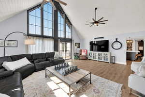 Living room featuring wood-type flooring, high vaulted ceiling, and ceiling fan