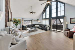 Living room featuring high vaulted ceiling, ceiling fan, and light hardwood / wood-style flooring