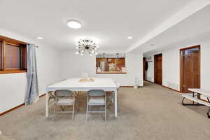 Dining space with light colored carpet and a chandelier