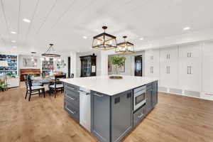 Kitchen featuring gray cabinets, a center island, pendant lighting, and stainless steel microwave