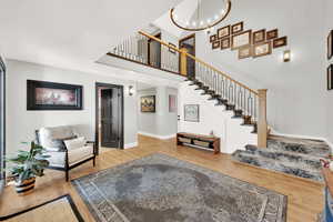 Foyer featuring wood-type flooring, a high ceiling, and a notable chandelier