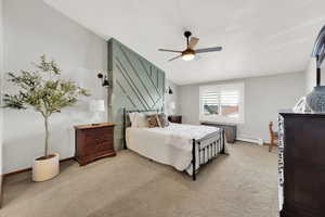 Carpeted bedroom featuring a baseboard heating unit and ceiling fan