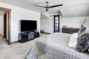 Bedroom featuring a barn door, carpet, and ceiling fan