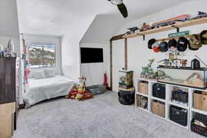 Carpeted bedroom with ceiling fan and lofted ceiling