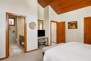 Carpeted bedroom with lofted ceiling, connected bathroom, and wood ceiling