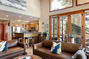 Living room with sink, light hardwood / wood-style floors, and a high ceiling