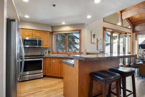 Kitchen featuring a breakfast bar, sink, kitchen peninsula, stainless steel appliances, and light hardwood / wood-style flooring