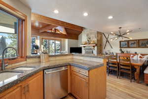 Kitchen with dishwasher, vaulted ceiling with beams, a textured ceiling, kitchen peninsula, and light wood-type flooring