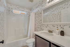 Full bathroom featuring shower / tub combo with curtain, vanity, and toilet