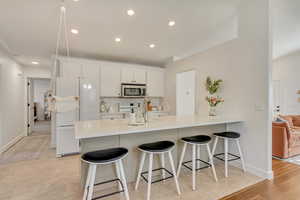 Kitchen with white cabinetry, a kitchen bar, decorative backsplash, kitchen peninsula, and white appliances