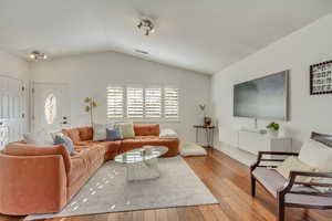 Living room with vaulted ceiling and light hardwood / wood-style flooring