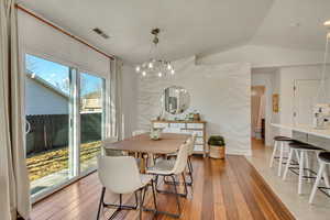 Dining space with lofted ceiling and light hardwood / wood-style flooring