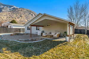 Rear view of property featuring a mountain view, an outdoor living space, a patio area, and a yard