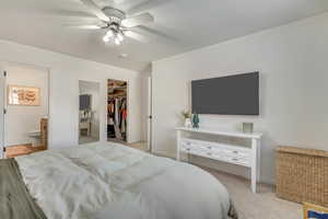 Bedroom with a spacious closet, ceiling fan, crown molding, ensuite bath, and a closet