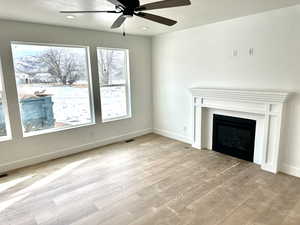 Family room with ceiling fan, fireplace, and light wood-type flooring.