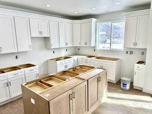 Kitchen with a kitchen island, white cabinets, and light hardwood / wood-style floors.