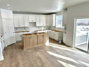 Kitchen featuring a center island, white cabinets, and light wood-type flooring.