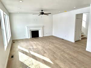 Family room with ceiling fan, fireplace, and light wood-type flooring.