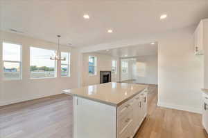 Kitchen featuring white cabinetry, decorative light fixtures, a center island, and a healthy amount of sunlight