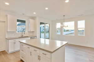 Kitchen with white cabinetry, a kitchen island, sink, and backsplash