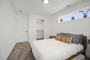 Carpeted bedroom featuring a walk in closet