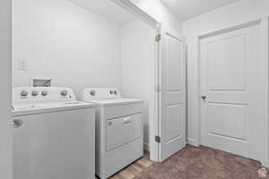 Laundry room with washer and clothes dryer and carpet