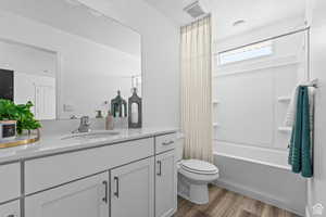 Full bathroom with vanity, hardwood / wood-style flooring, shower / washtub combination, and toilet