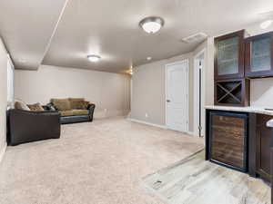 Living room featuring bar, beverage cooler, light carpet, and a textured ceiling