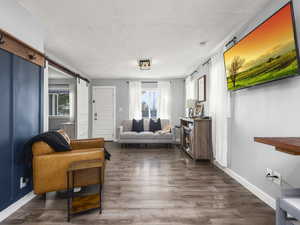 Living room featuring a barn door, dark hardwood / wood-style flooring, and a textured ceiling