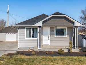 Bungalow-style house featuring a garage, an outdoor structure, and a front lawn