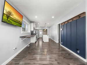 Kitchen with decorative light fixtures, white cabinets, stainless steel appliances, a barn door, and dark wood-type flooring