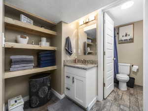 Bathroom featuring vanity, hardwood / wood-style floors, toilet, and a textured ceiling